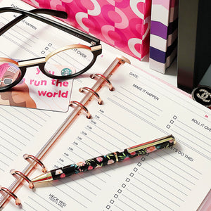 a desk showing a notebook, glasses, and the Future Is female pen