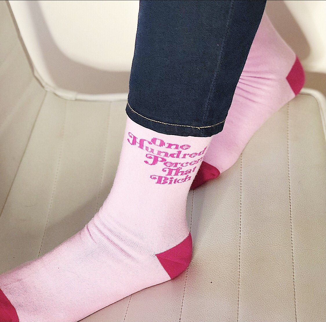 A person's feet wearing pink socks that say 100% that B